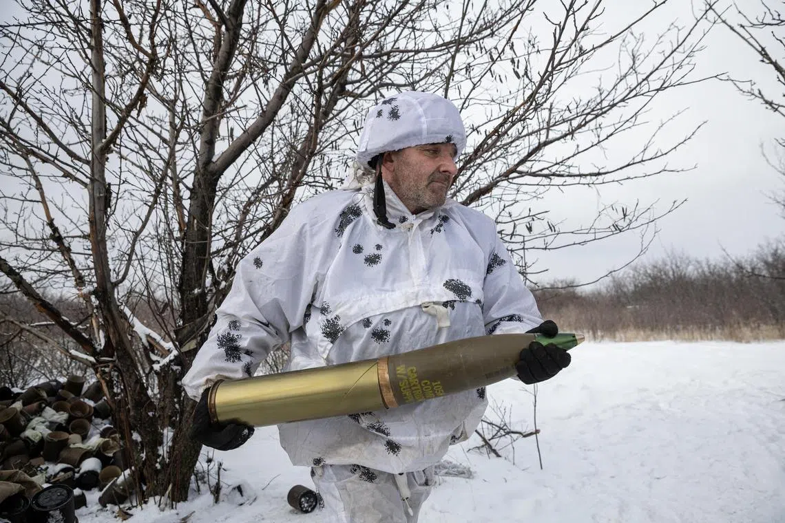 A Ukrainian serviceman carries a shell to load into a howitzer, for firing at Russian positions on the front line, near Bahmut, in Ukraine's Donetsk region, on Feb 16, 2023.