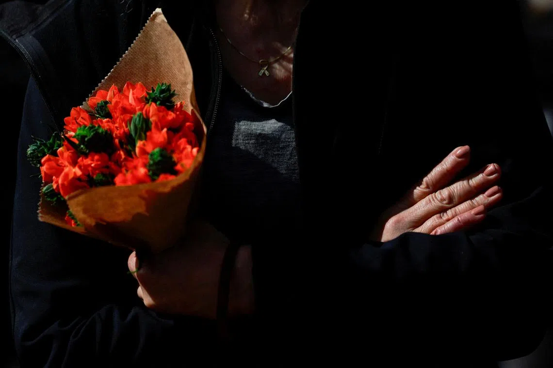 A woman holding a bouquet on the day the bodies of deceased Israeli hostages, who were kidnapped during the deadly October 7, 2023 attack by Hamas, are handed over under the terms of a ceasefire between Hamas and Israel, in Tel Aviv, Israel, on Feb 20, 2025. 