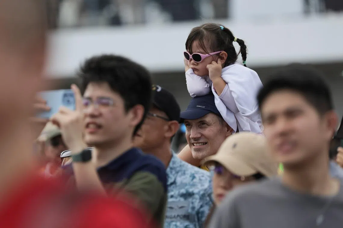 A child shielding her ears from the roaring planes as visitors watch the aerial display at the Singapore Airshow at Changi Exhibition Centre, Feb 24, 2024.