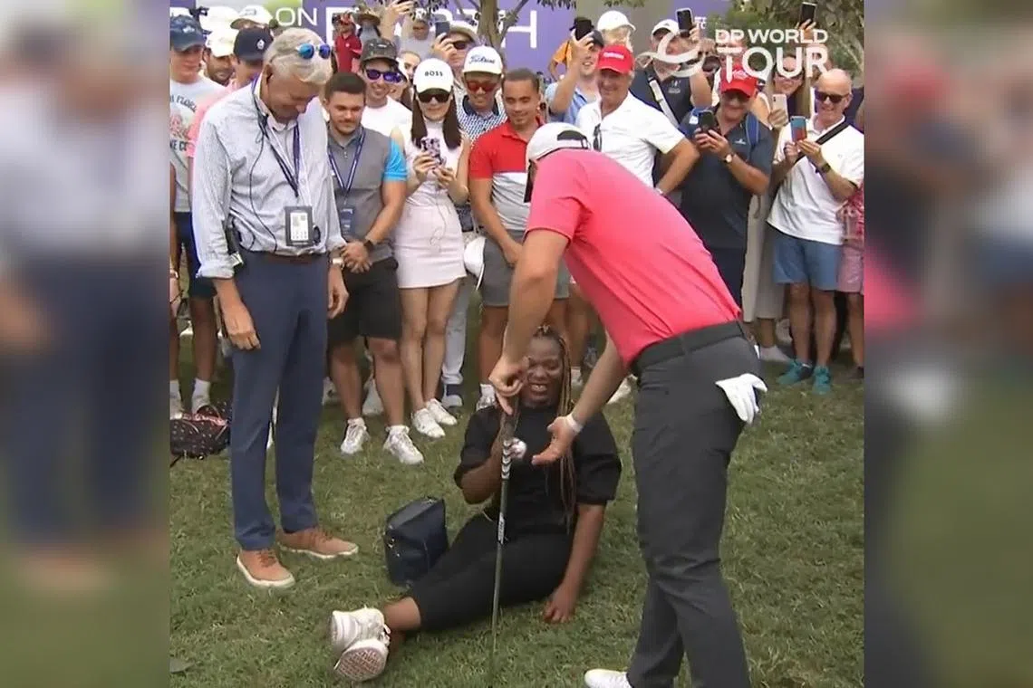 A spectator hands Rory McIlroy his ball in front of the tournament referee, after it landed in her lap.