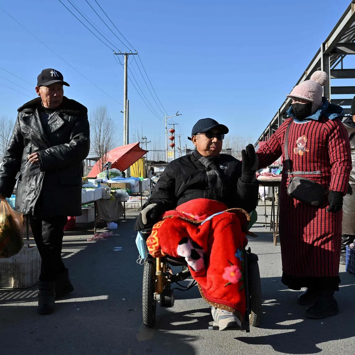 People in winter clothes trade at a traditional market in a neighbourhood affected by the heating subsidy policy, in Baoding city, northern China's Hebei province on Jan 7. 