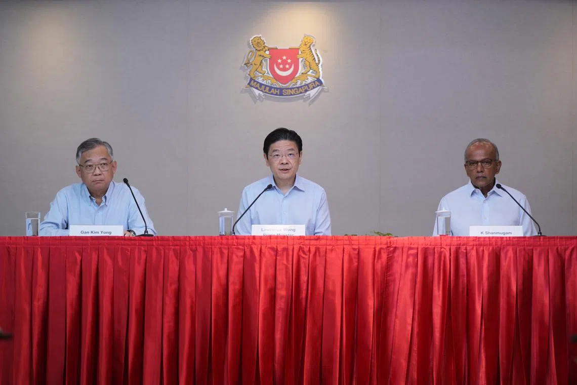 PM Lawrence Wong (centre) with DPM Gan Kim Yong (left) and Mr K. Shanmugam at a press conference on May 21.