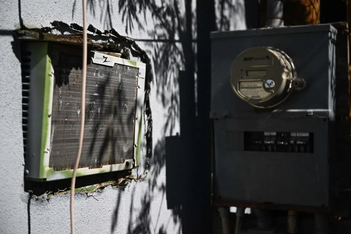 A window mounted air conditioning unit hangs through a wall of a mobile home next to an electrical panel during a record heat wave in Phoenix, Arizona on July 20, 2023. A study in 2022 by Arizona State University found that while mobile homes make up just five percent of all housing in metropolitan Phoenix, they account for 30% of heat-related deaths in the city. (Photo by Patrick T. Fallon / AFP)
