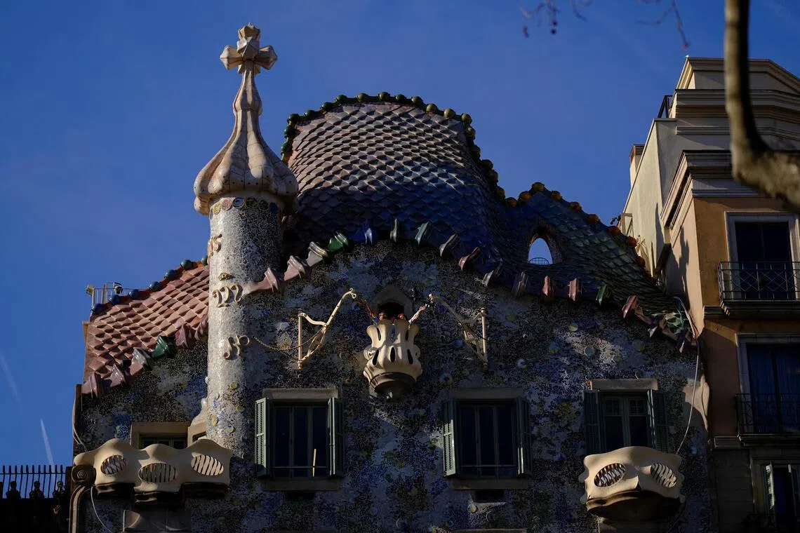Tourists pose for a picture on a balcony of Casa Batllo, designed by architect Antoni Gaudi, at Passeig De Gracia in Barcelona, Spain on Feb 24, 2026. 