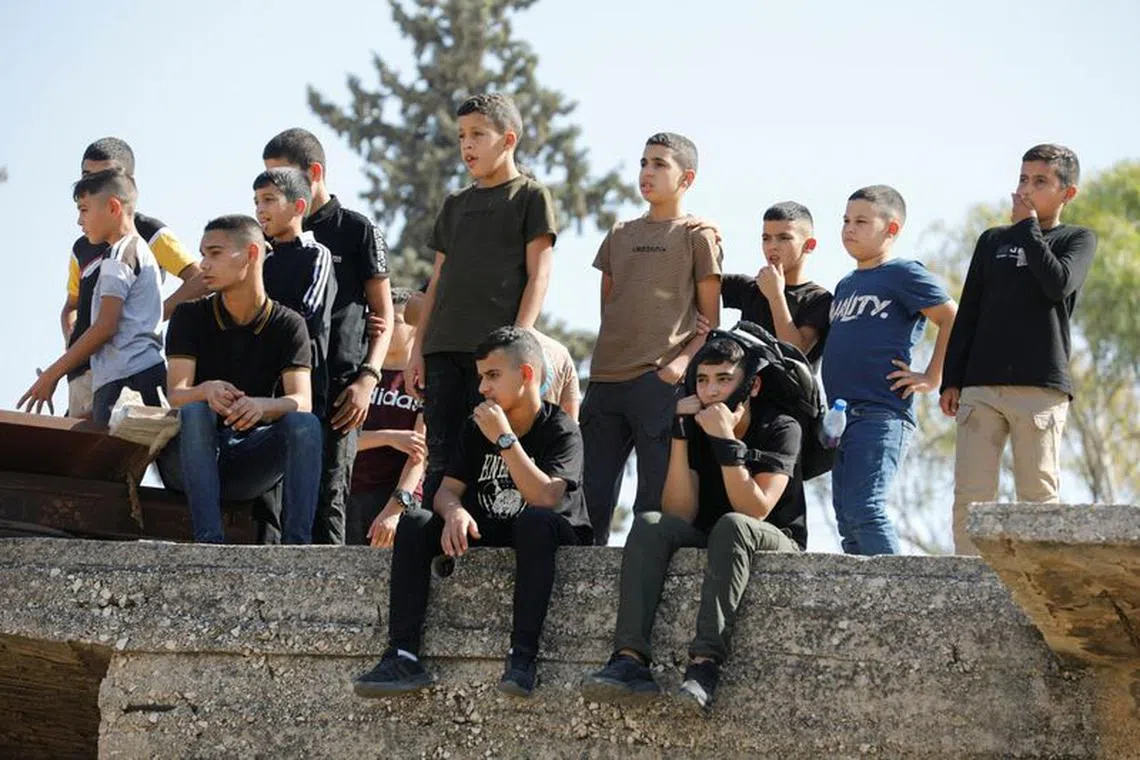 Boys watch the funeral ceremony of three Palestinians killed in an Israeli strike at Jenin refugee camp in the Israeli-occupied West Bank October 25, 2023. REUTERS/Raneen Sawafta