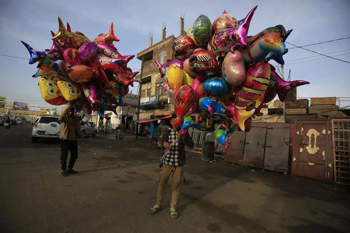 Street vendors holding balloons for sale during Eid al-Fitr celebrations in Sana'a, Yemen, on April 10, 2024. 