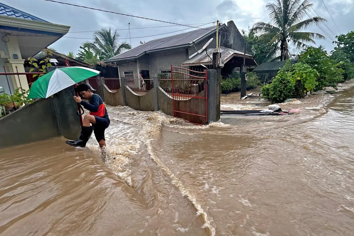 TOPSHOT - A man wades through floodwaters brought about by heavy rains at a residential neighbourhood in Propseridad town, Agusan del Sur province on southern Mindanao island on February 1, 2024. Floods and landslides triggered by torrential rain have killed six people in the Philippines, with one other person missing, rescuers said February 1. (Photo by Erwin MASCARINAS / AFP)