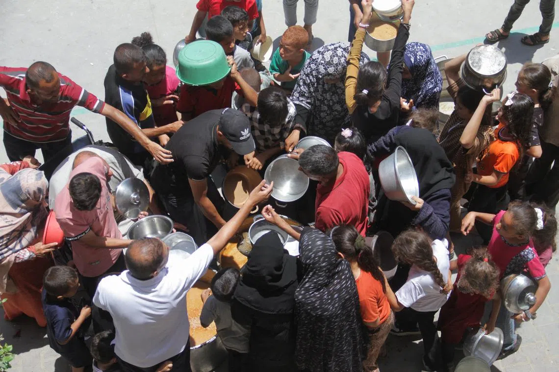 FILE PHOTO: Palestinians gather to receive food cooked by a charity kitchen, as they struggle with food scarcity, basic necessities amid the conflict between Israel and Hamas continues, in Jabalia refugee camp, in the northern Gaza Strip, June 19, 2024. REUTERS/Mahmoud Issa/File Photo