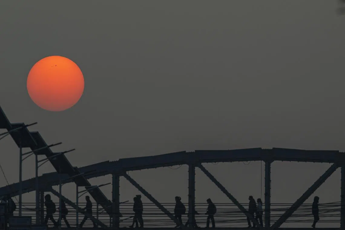 People cross a pedestrian bridge as the sun rises in Kathmandu on Feb 28, 2023.