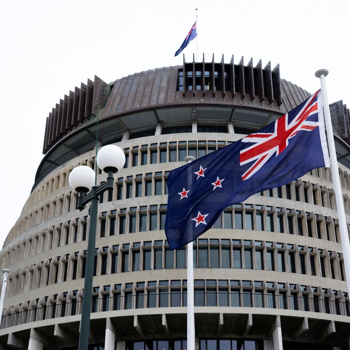 New Zealand's flag flutters in front of 'The Beehive', the executive wing of the New Zealand Parliament Buildings, in Wellington, New Zealand, September 24, 2025. REUTERS/Marty Melville