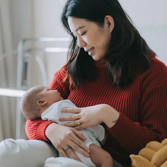 Young asian woman carrying newborn baby
