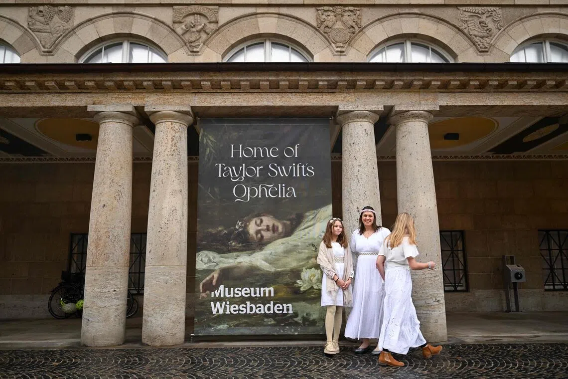 Fans of US singer-songwriter Taylor Swift pose next to a placard with the title 'Home of Taylor Swift's Ophelia' outside the Museum in Wiesbaden, western Germany, on Nov 2. 