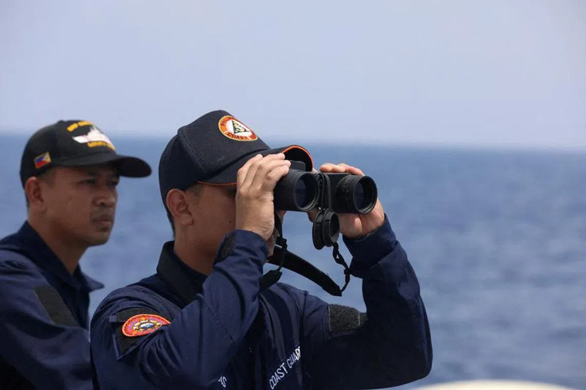 FILE PHOTO: A Philippine Coast Guard personnel looks through a binocular while conducting a resupply mission for Filipino troops stationed at a grounded warship in the South China Sea, October 4, 2023. REUTERS/Adrian Portugal/File Photo