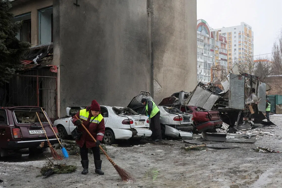 Municipal workers remove debris next to damaged cars outside an apartment building hit by a Russian drone strike on Thursday, amid Russia's attack on Ukraine, in Kharkiv, Ukraine February 26, 2026. REUTERS/Vyacheslav Madiyevskyy