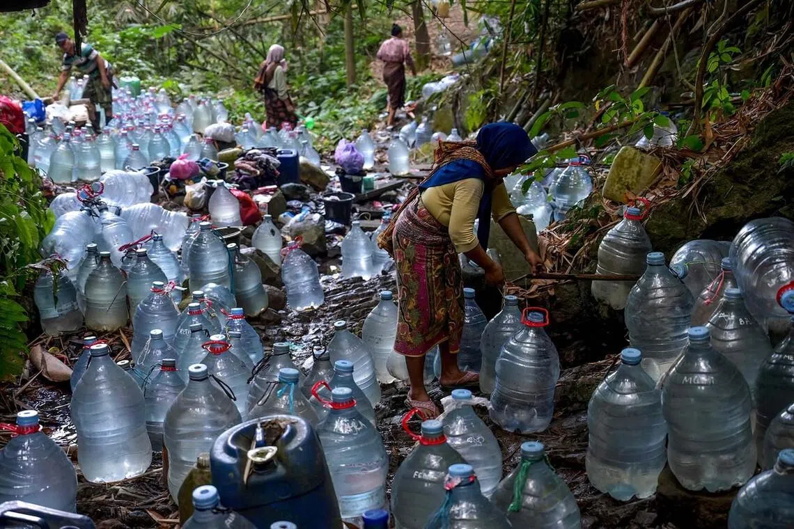 TOPSHOT - Villagers collect spring water with bottles at Gunung Batur village in Cilegon, Banten province, on July 17, 2026, after struggling to access groundwater at their homes in part due to the impact of El Nino, which has brought a prolonged dry season and triggered extreme drought, threatening food security in various regions of Indonesia. Indonesia's Meteorology, Climatology, and Geophysics Agency (BMKG) has warned that the country's dry season will be more intense and prolonged than average -- in part due to the El Nino weather pattern heightening risks of wildfires and droughts. (Photo by BAY ISMOYO / AFP)