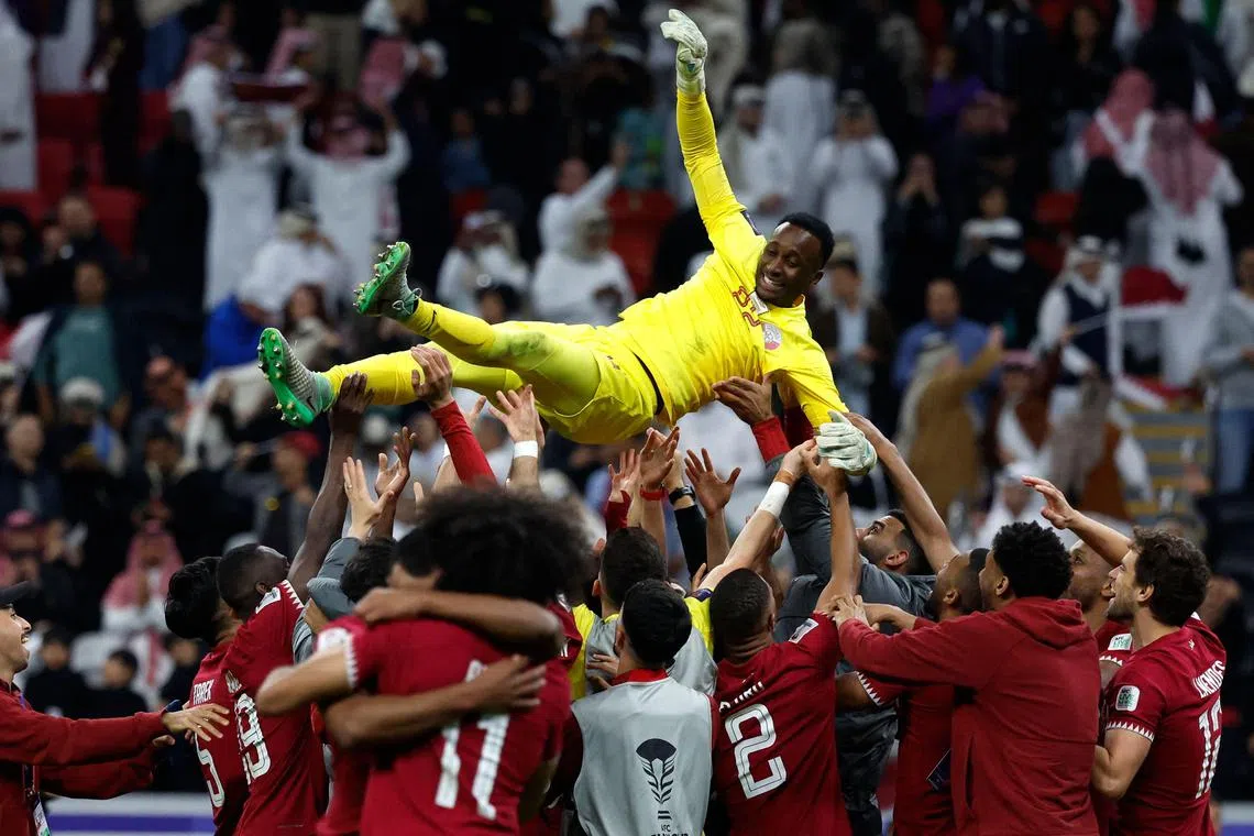 Qatar's players lift goalkeeper Meshaal Barsham after winning the quarter-final match against Uzbekistan.