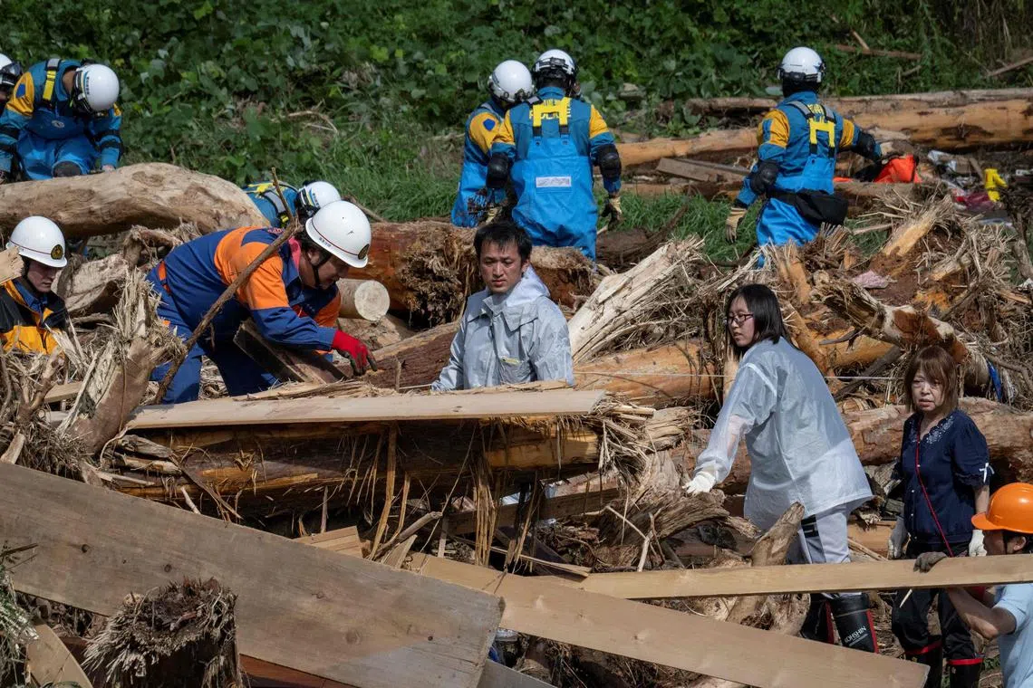 MrTakaya Kiso (centre) searching for his missing 14-year-old daughter among debris washed away from flooding along the Tsukada river on Sept 23. 