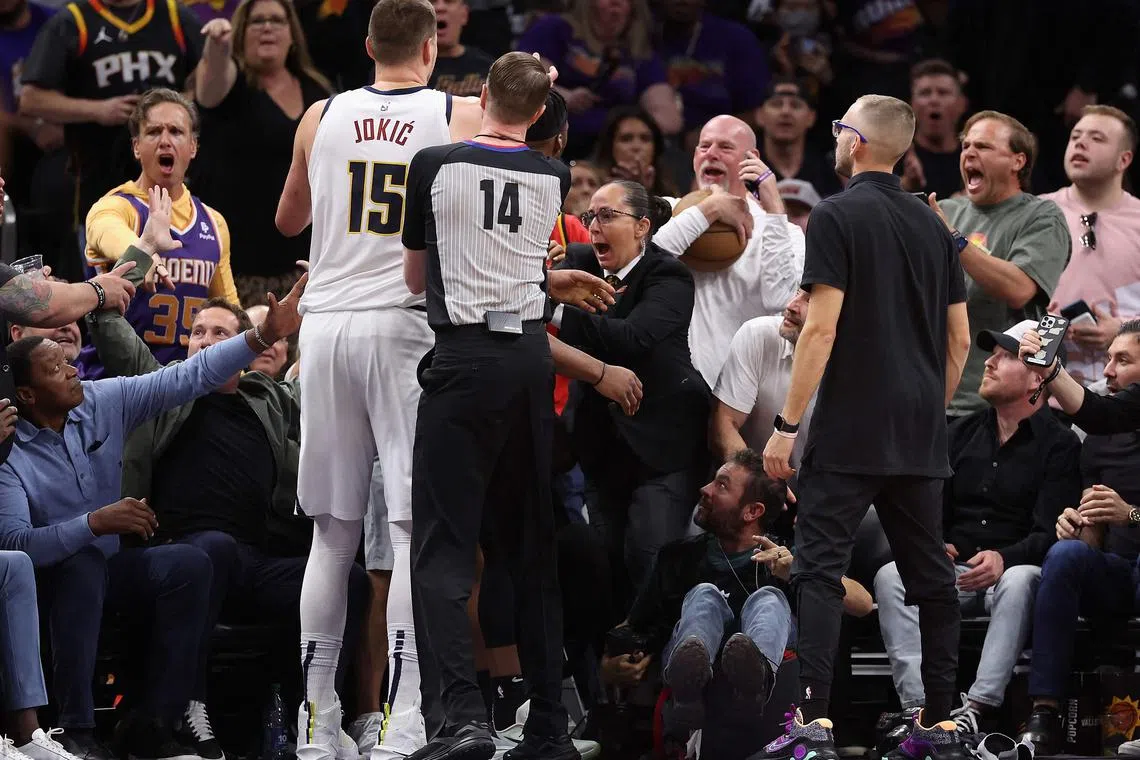 Denver's Nikola Jokic (No. 15) reaching for the basketball after pushing off Phoenix Suns owner Mat Ishbia (left) during Game 4 of the NBA Western Conference semi-finals on Sunday. 