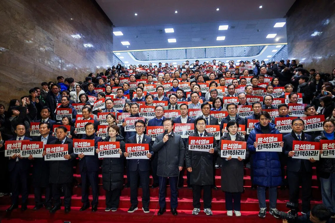 South Korea's main opposition Democratic Party leader Lee Jae-myung and lawmakers attending a press conference after South Korean President Yoon Suk Yeol, who declared martial law which was reversed hours later, survived an impeachment motion, at the National Assembly in Seoul, South Korea, Dec 7, 2024. The signs read: "Punish the rebellion leader" and "Impeach Yoon Suk Yeol".