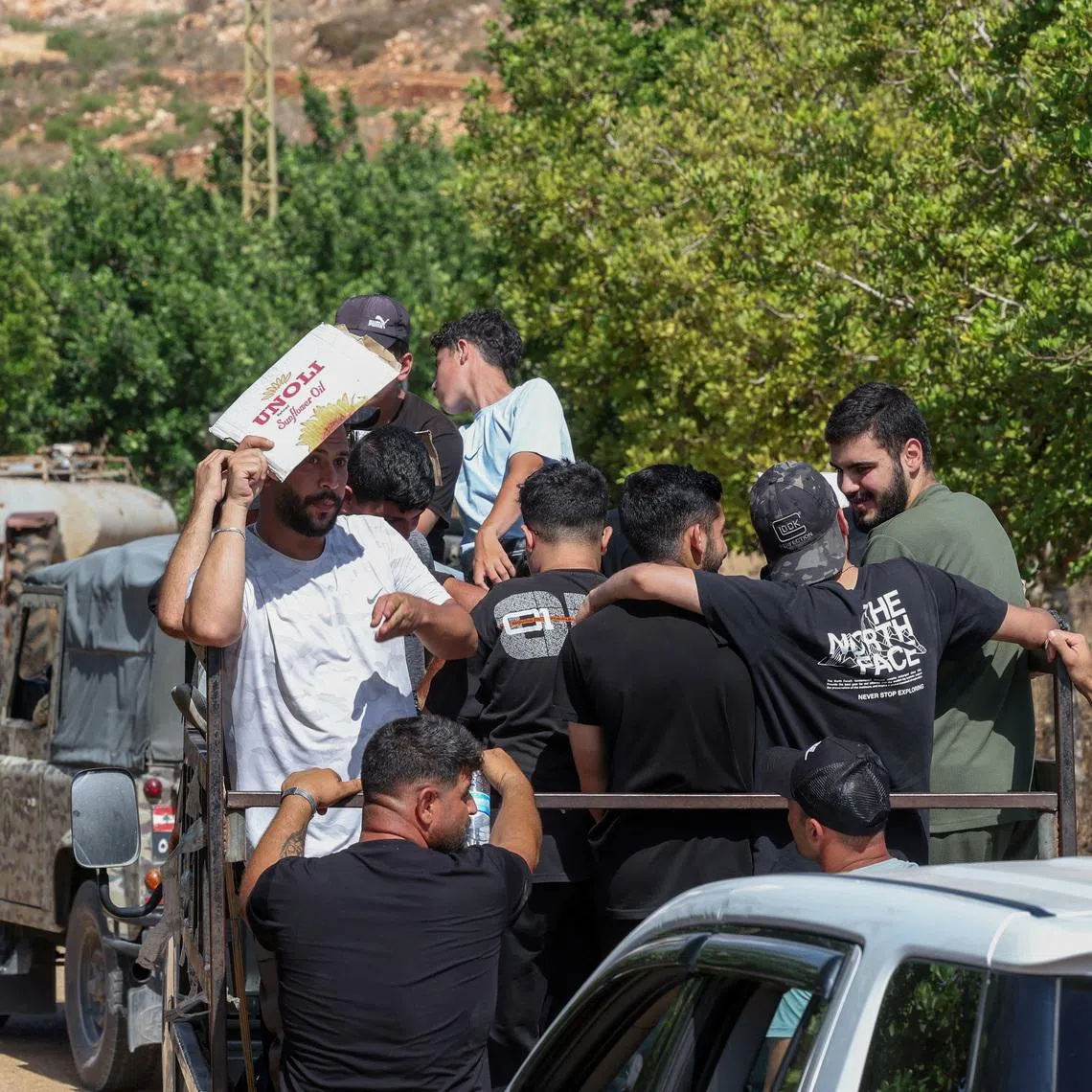A man shields himself from the sun as residents wait to enter the town of Zawtar al-Gharbiyeh, following the withdrawal of Israeli forces under a U.S.-brokered plan, next to Lebanese soldiers, in southern Lebanon, July 24, 2026. REUTERS/Aziz Taher