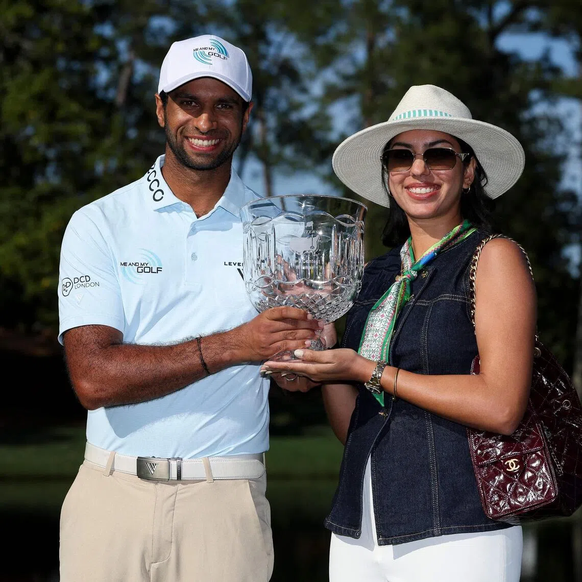 Aaron Rai of England posing with the Crystal Pedestal Bowl and his wife Gaurika Bishnoi after winning the Par-Three Contest ahead of the 2026 Masters Tournament at Augusta National Golf Club on April 8, 2026 in Augusta, Georgia.