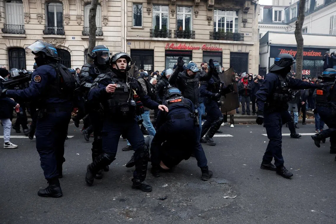 French riot police apprehend protesters, amid clashes in Paris over pension reforms, on Jan 19, 2023.