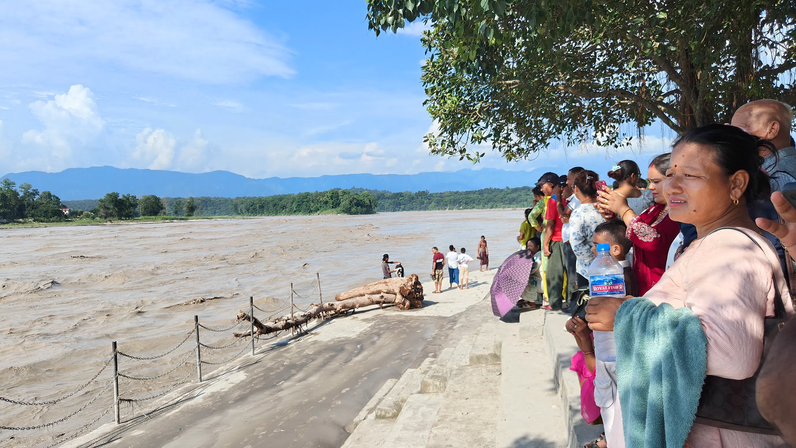 Curious onlookers look at the swollen Narayani river in Bharatpur in Chitwan district. Many bodies washed downstream from northern Nepal have been found along its bank.