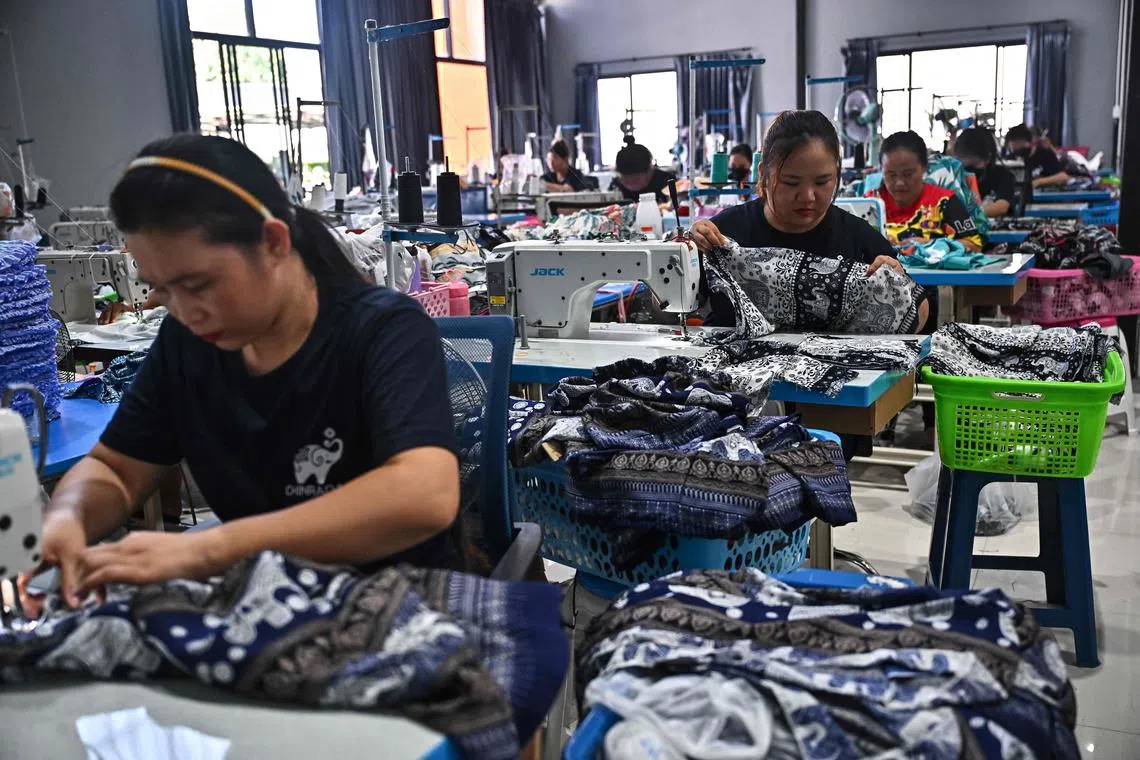 Workers sewing clothing with elephant print at Chinrada Garment co. in the northern Thai province of Chiang Mai. 