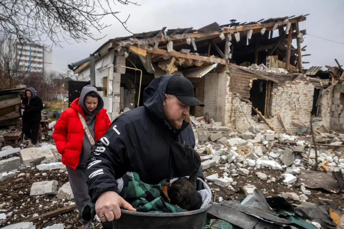 Mr Ruslan Malashok carrying an injured dog after his mother's home was hit during a night of Russian missile and drone strikes across Ukraine, in Novi Petrivtsi, near Kyiv, on Dec 6.