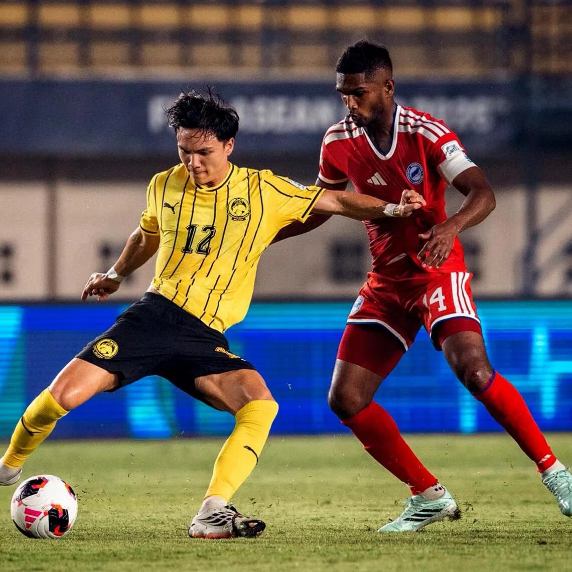 Singapore captain Hariss Harun (right) tussling with Stuart Wilkin during the Lions’ 6-0 FIFA ASEAN Cup loss to Malaysia at the Si Jalak Harupat Stadium in Bandung on Oct 1.