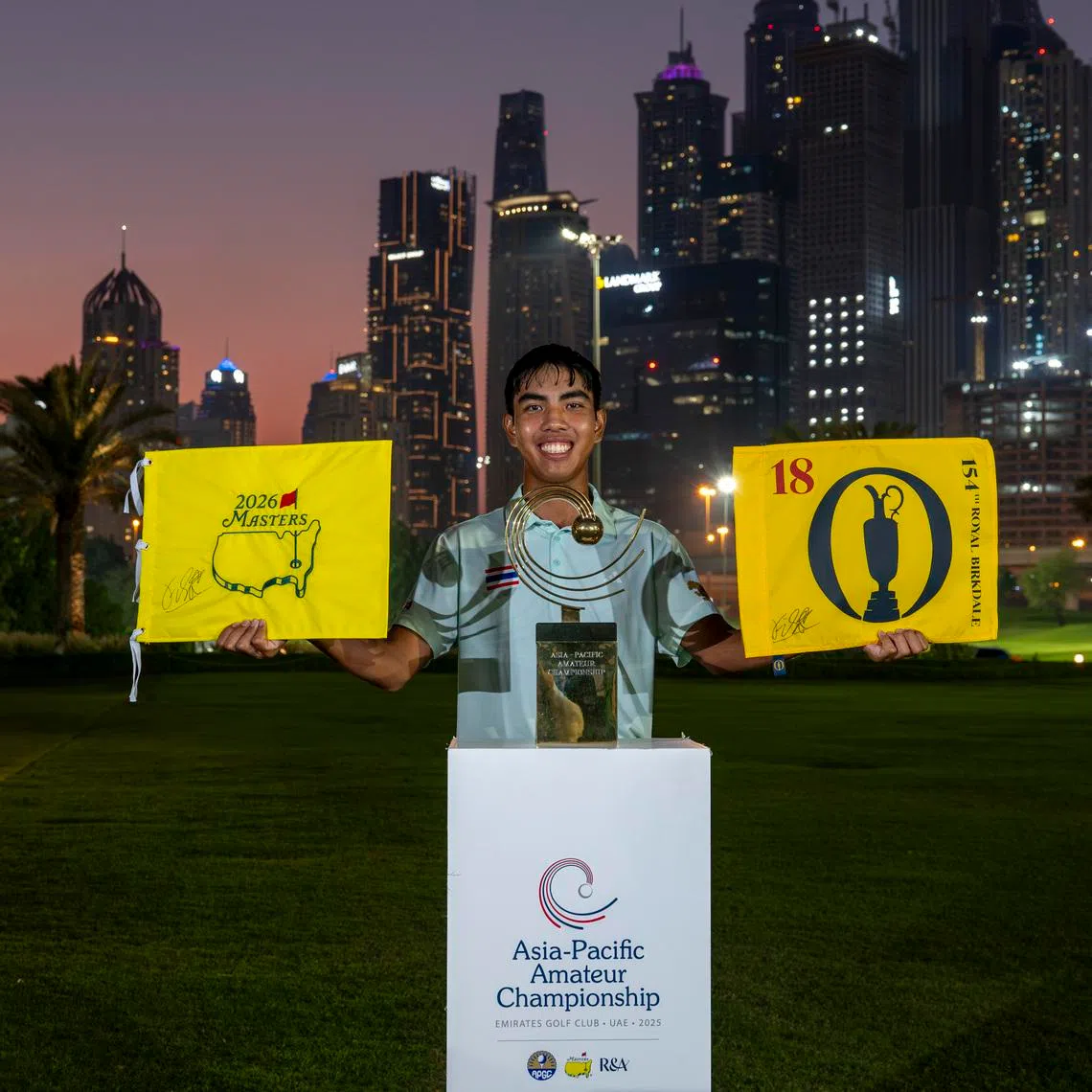 Fifa Laopakdee lifts the 154th Open Championship flag and the Masters flag alongside the Asia-Pacific Amateur Championship trophy after winning the 2025 Asia-Pacific Amateur Championship in Dubai on Oct 26, 2025.