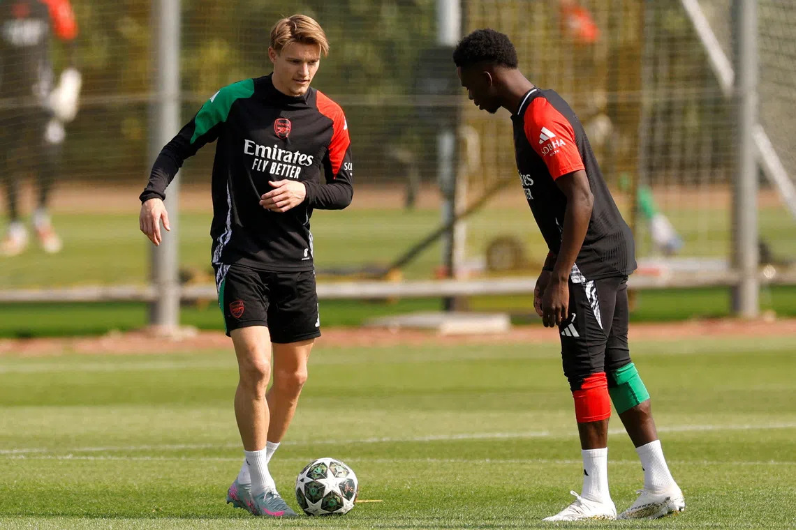 FILE PHOTO: Soccer Football - Champions League - Arsenal Training - Arsenal Training Centre, London Colney, Britain - April 28, 2025 Arsenal's Martin Odegaard with Bukayo Saka during training Action Images via Reuters/Andrew Couldridge/File Photo
