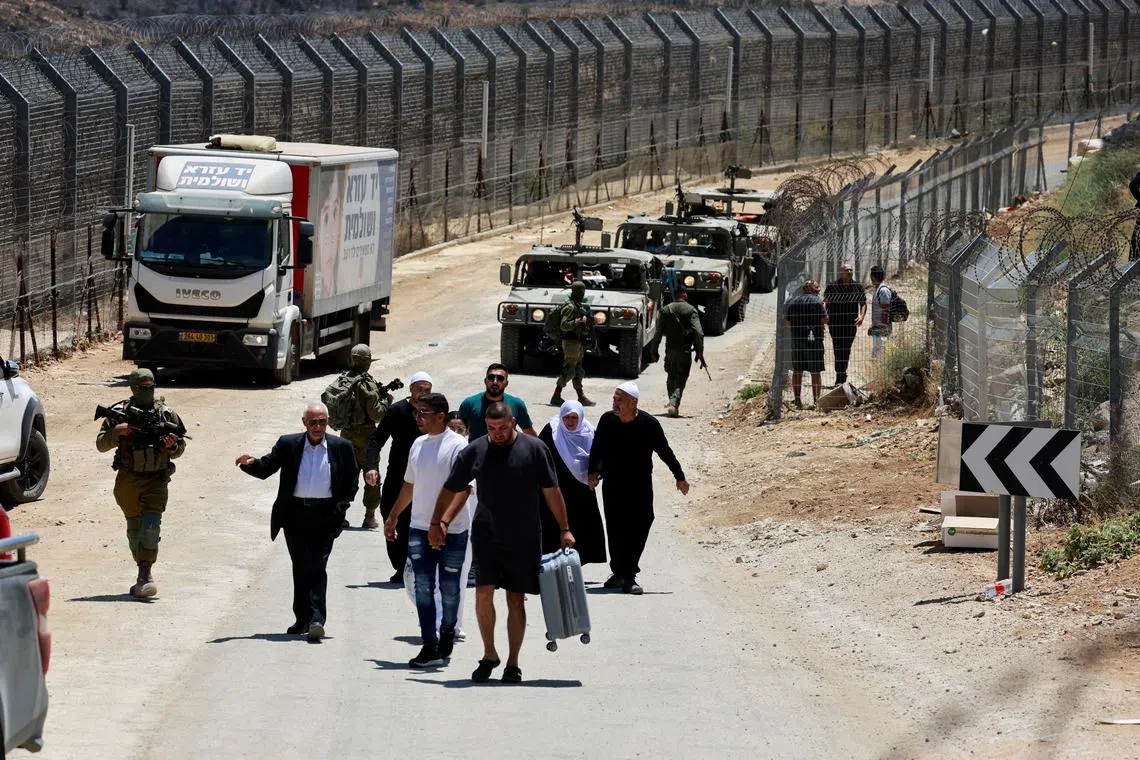 Syrian people are escorted by the Israeli military as they walk from Majdal Shams back to Syria, along the ceasefire line between the Israeli-occupied Golan Heights and Syria, amid the ongoing conflict in the Druze areas in Syria, in Majdal Shams, July 17, 2025. REUTERS/Ammar Awad