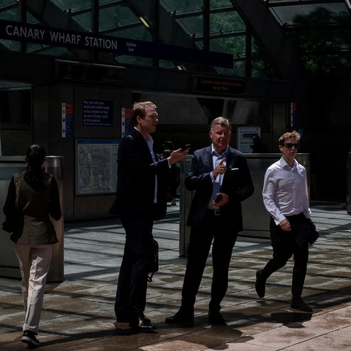 Workers talk outside Canary Wharf underground station in London, on June 9.