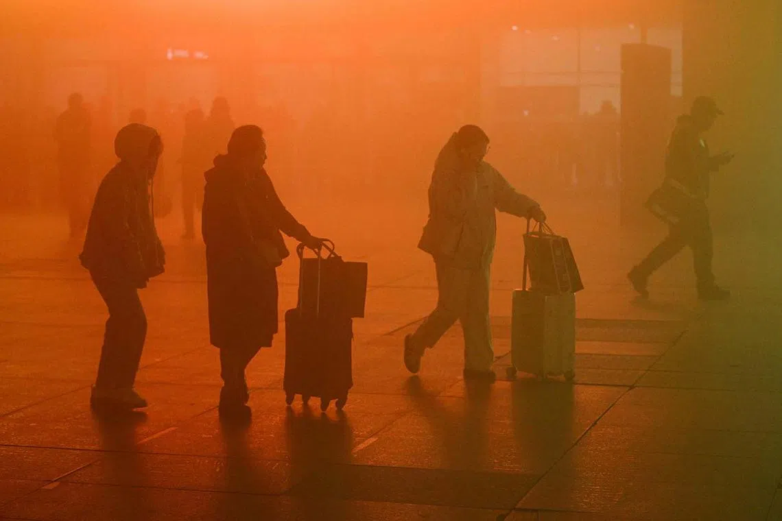 TOPSHOT - The photo taken on November 20, 2024 shows people walking with their luggages at a train station during a foggy day in Yinchuan, in northern China's Ningxia region. (Photo by STRINGER / AFP) / China OUT