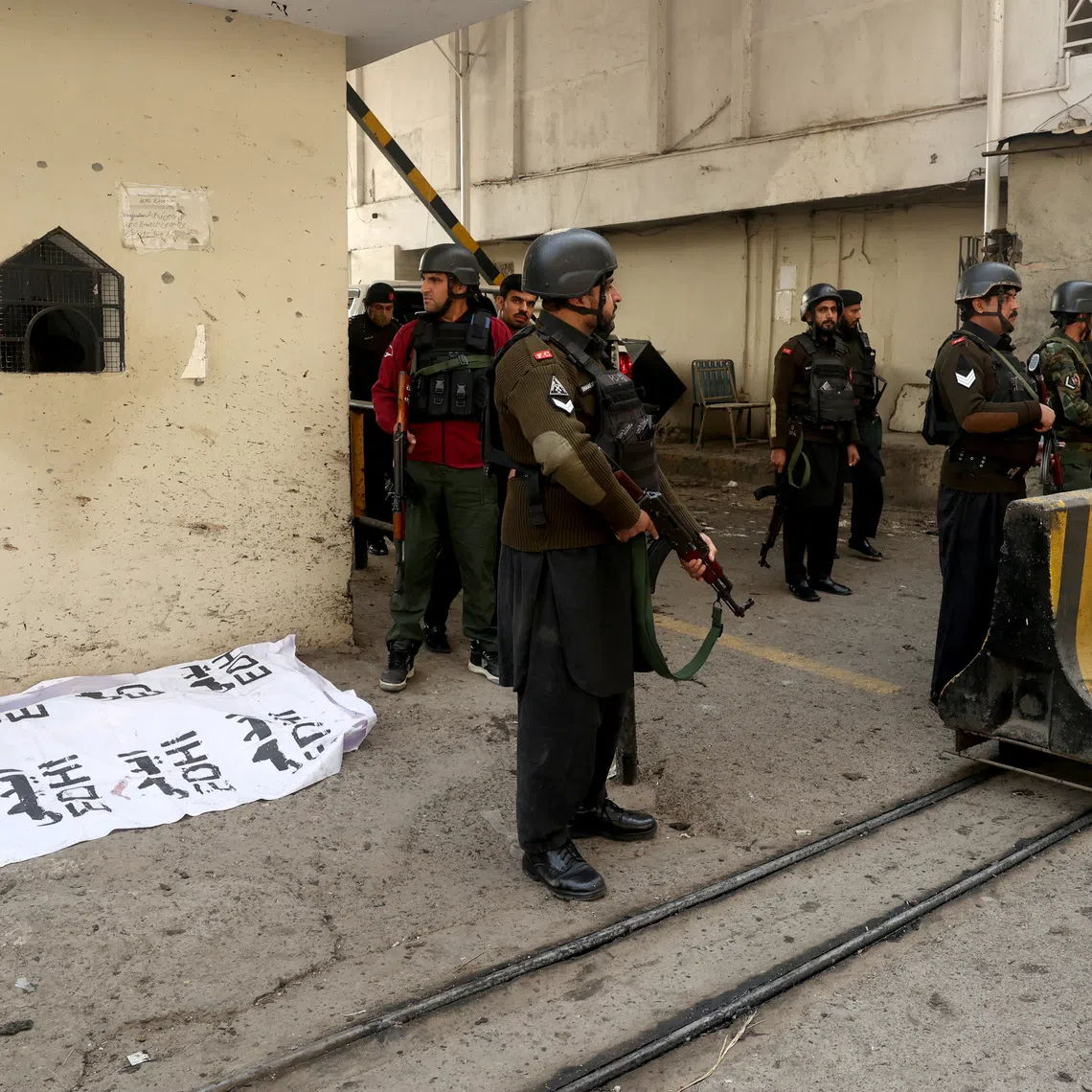 Paramilitary soldiers standing near a body covered with a sheet, after suicide bombers targeted the headquarters of a Pakistani paramilitary force in Peshawar on Nov 24.