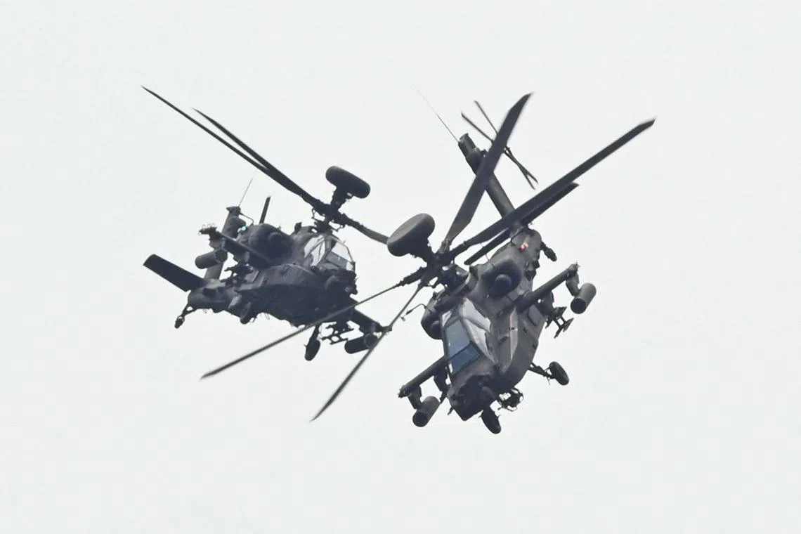 TOPSHOT - Two US-made Apache attack helicopters, from Taiwan’s Army Airborne Special Forces, demonstrate their combat skills during a military open house event in Hsinchu on September 21, 2023. (Photo by Sam Yeh / AFP)