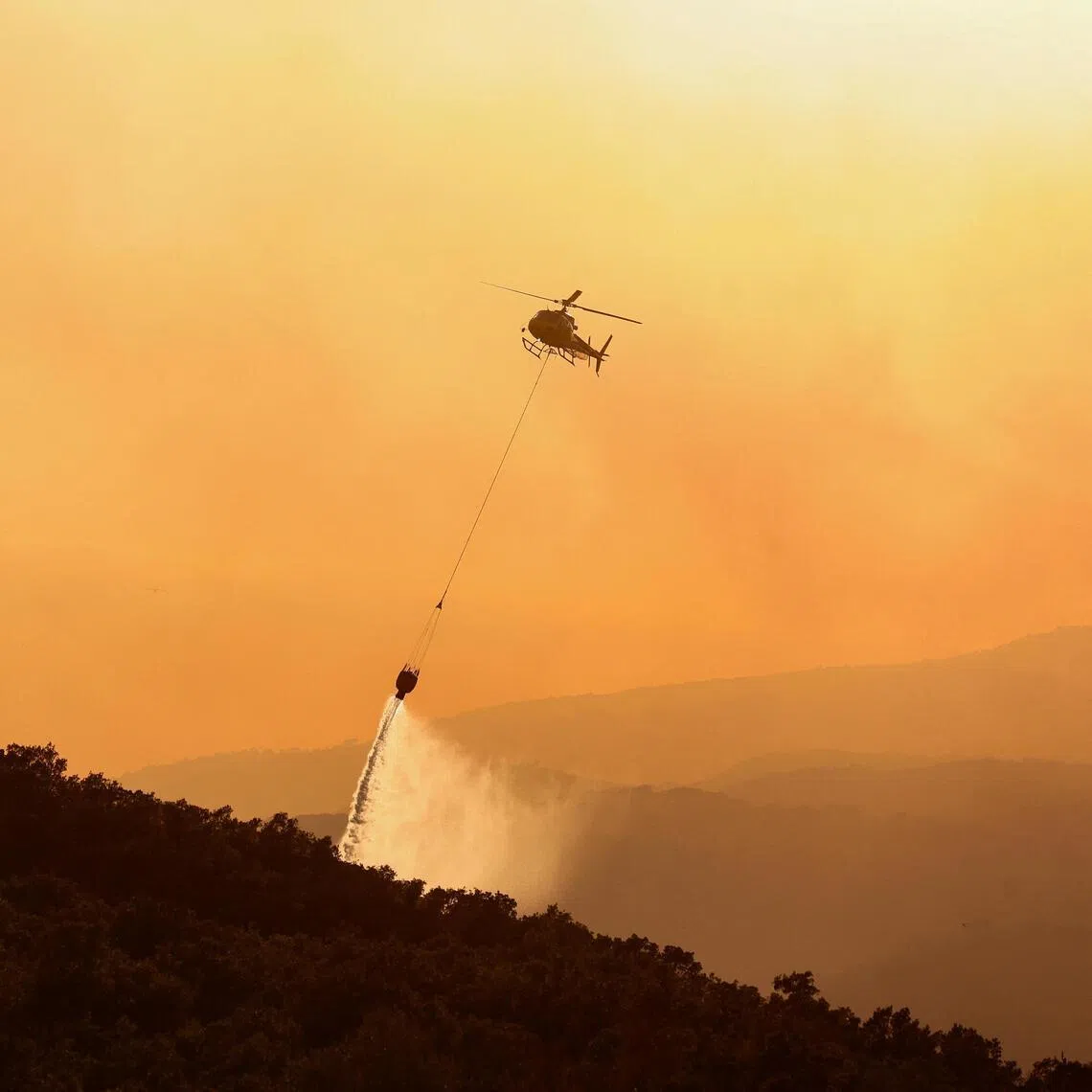 A firefighting helicopter battles a wildfire near Calonge, Spain, July 3, 2026. REUTERS/Bruna Casas
