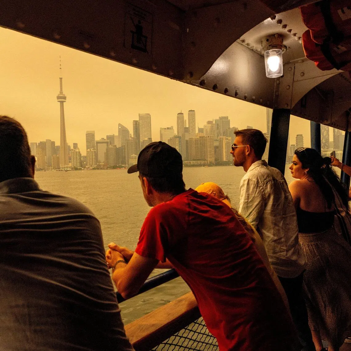 People ride the ferry to Toronto Island, as wildfire smoke from northwestern Ontario fills the sky, in Ontario, Canada, on July 15.
