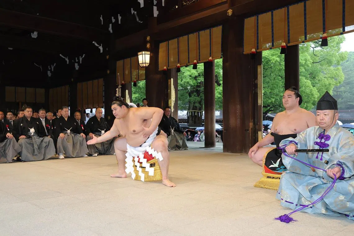 Japanese sumo wrestler and new yokozuna, or grand champion, Onosato (centre) performs the ring-entering ceremony at Tokyo's Meiji Shrine in Tokyo on May 30.