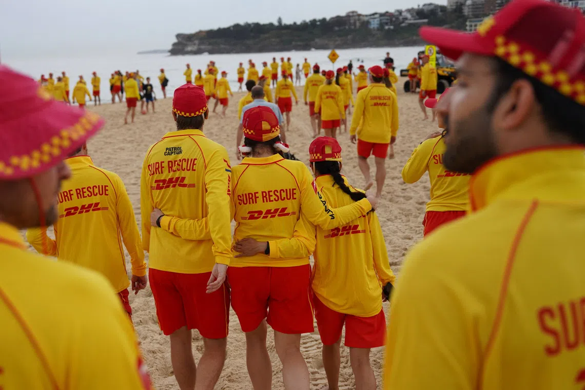 Members of Bondi Surf Life Saving Club and North Bondi Surf Life Saving Club walk towards Bondi Beach during an event to stand shoulder to shoulder as they observe three minutes of silence to honour victims, responders, and lifesavers following the mass shooting that targeted a Jewish Hanukkah celebration at Bondi Beach on December 14, in Sydney, Australia, December 20, 2025. REUTERS/Audrey Richardson