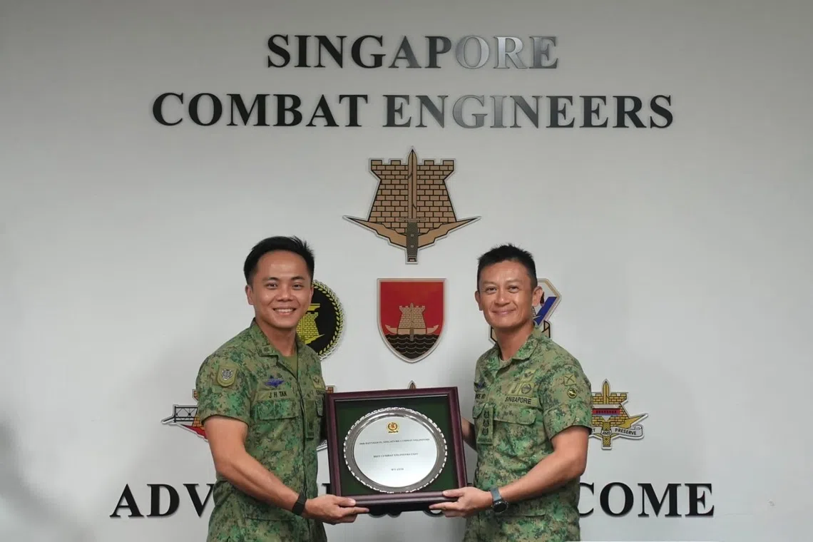 brandon tan holding the best combat support unit award received by 30th battalion, singapore combat engineers