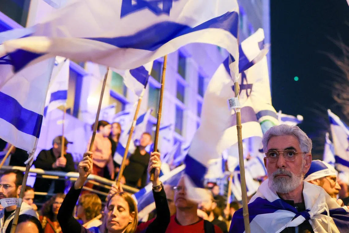 People hold Israeli flags during a demonstration against the judicial reforms in Tel Aviv, on March 11, 2023.