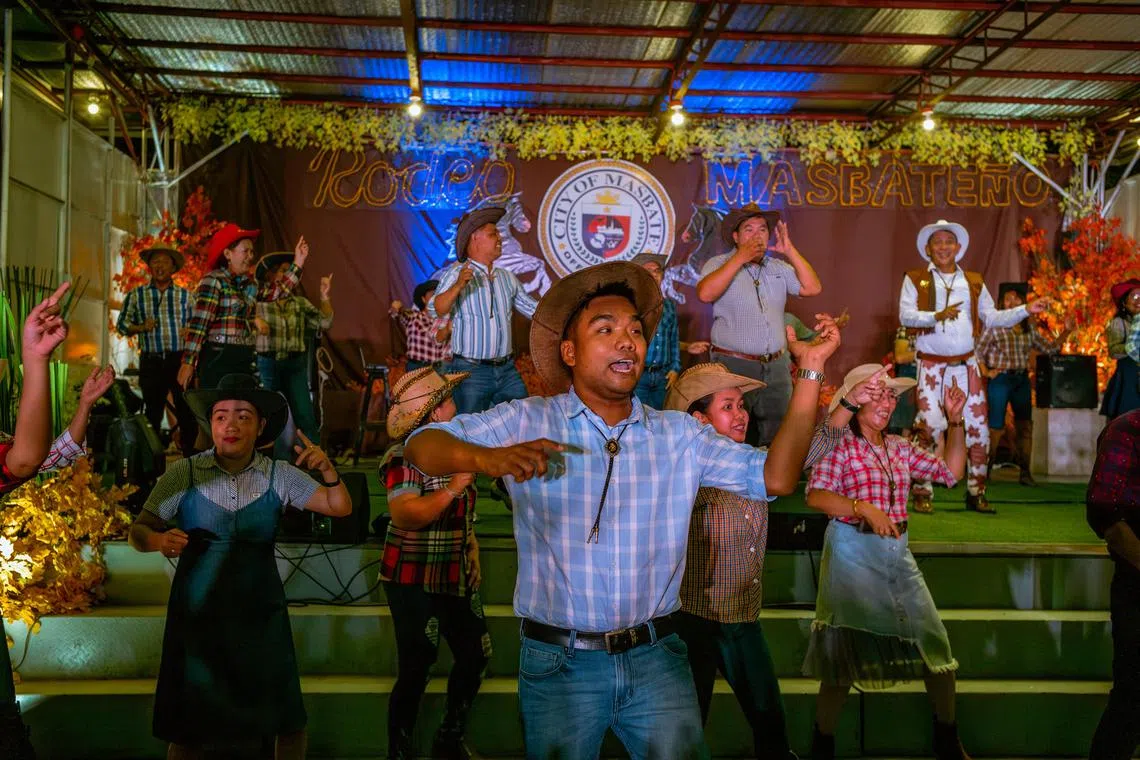 Patrons swing to the music during the Rodeo Festival, in Masbate City, Philippines on April 12, 2023. In the Philippines, men and women compete in the annual rodeo, which celebrates a thriving cowboy culture with roots in the Spanish and American colonial eras. (Jes Aznar/The New York Times)