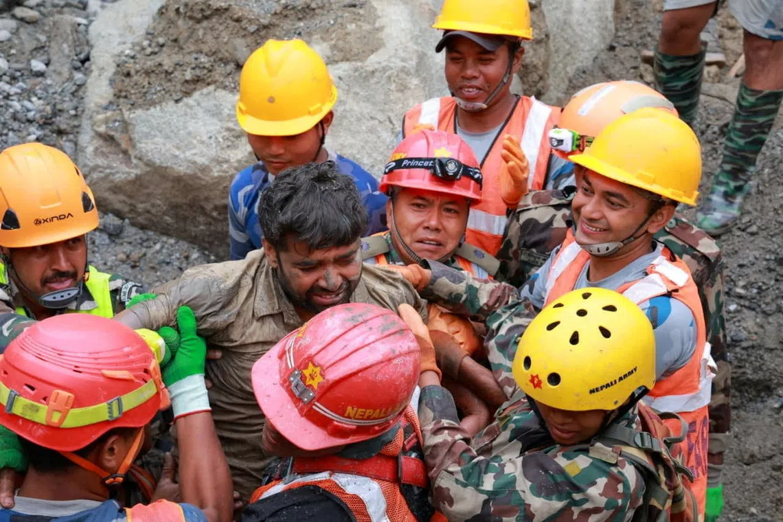 Survivor Sanjay Sah is carried by members of a search and rescue team.