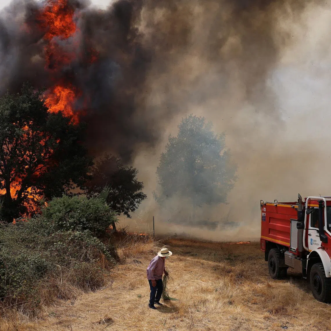 FILE PHOTO: A person stands near an emergency vehicle, as a wildfire rages in Veiga das Meas, near Verin, Ourense province, Galicia, Spain, August 16, 2025. REUTERS/Nacho Doce/File Photo