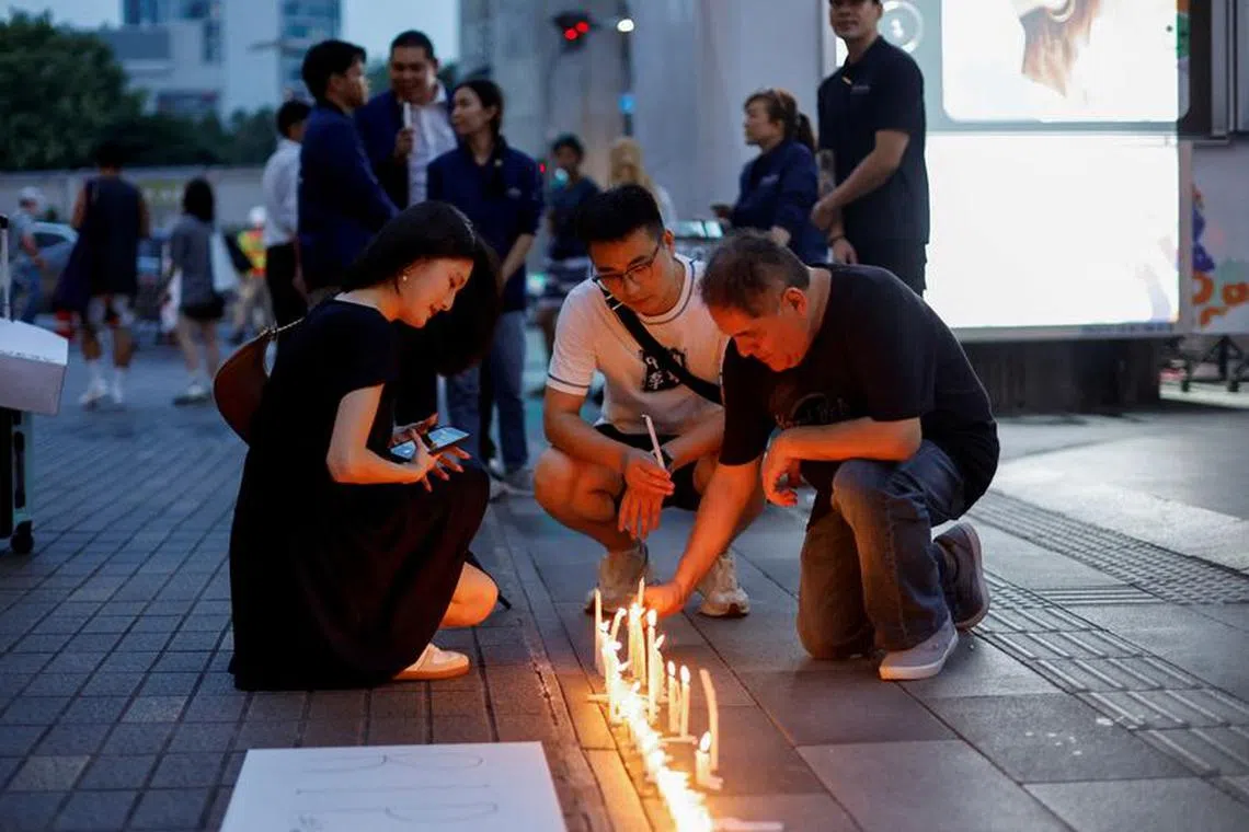 FILE PHOTO: Helen Yi, a tourist from Taiwan, looks at candles placed outside the luxury Siam Paragon shopping mall where Thai police arrested a teenage gunman who is suspected of killing foreigners and wounding other people in a shooting, in Bangkok, Thailand, October 4, 2023. REUTERS/Jorge Silva/File Photo
