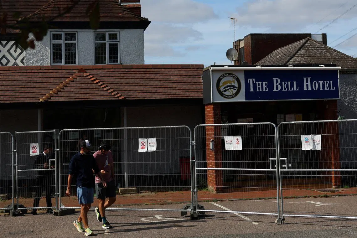 FILE PHOTO: Men walk past The Bell Hotel, following Tuesday's High Court ruling in London that granted a temporary injunction to stop asylum seekers from being housed at the site, in Epping, Britain, August 20, 2025. REUTERS/Isabel Infantes/File photo