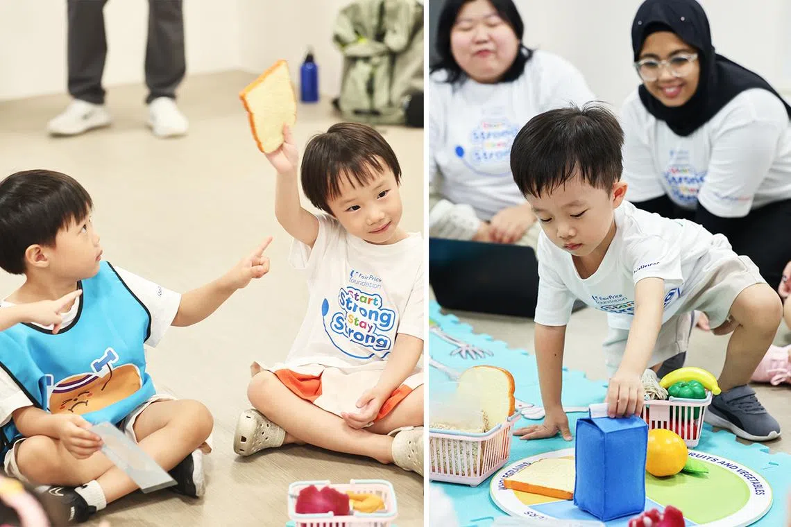 Asian preschool students holding up toy food while teachers look at them 