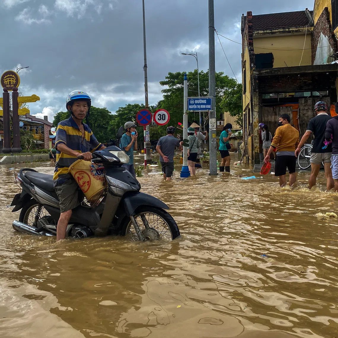 People wade through a flooded street, as a motorist looks on, in Hoi An, following deadly floods in central Vietnam, October 31, 2025. REUTERS/Thinh Nguyen